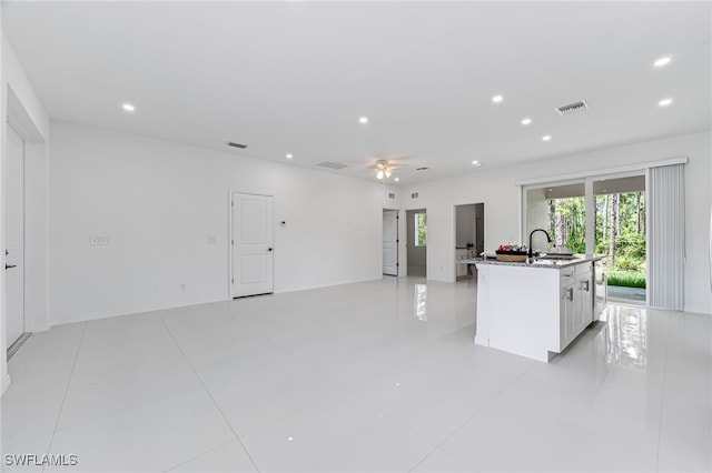 kitchen featuring white cabinets, light tile patterned floors, a center island with sink, and sink