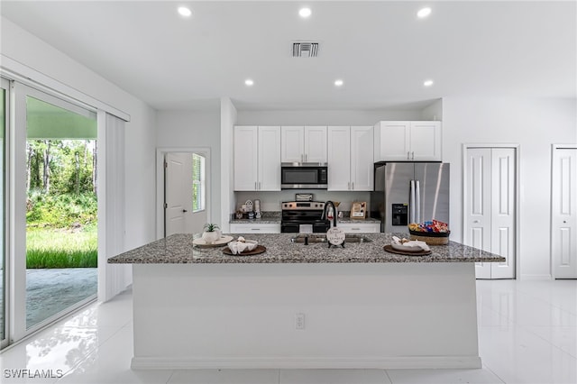 kitchen featuring white cabinets, stone counters, an island with sink, and appliances with stainless steel finishes