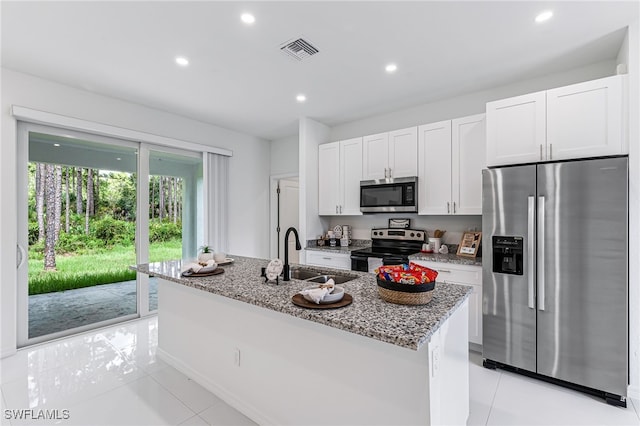 kitchen featuring light stone countertops, stainless steel appliances, a kitchen island with sink, sink, and white cabinets