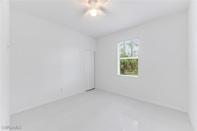 tiled spare room with ceiling fan