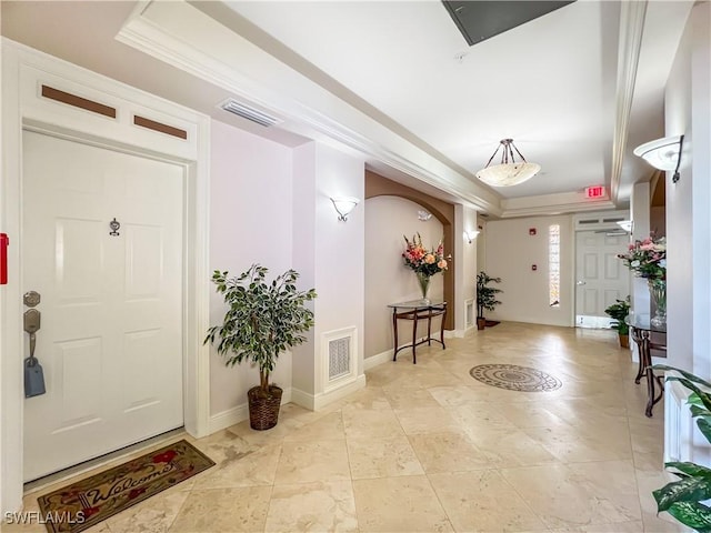 foyer with a raised ceiling and ornamental molding