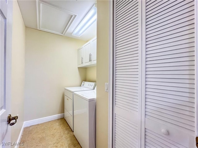 washroom featuring light tile patterned floors, baseboards, washing machine and clothes dryer, attic access, and cabinet space