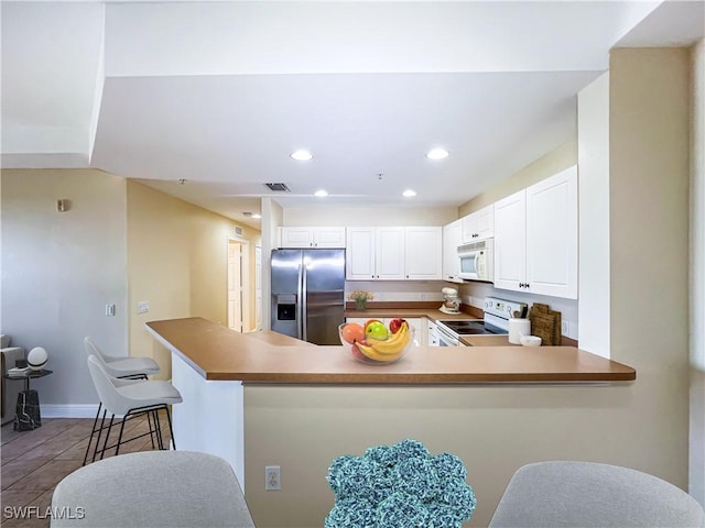 kitchen featuring white cabinetry, white appliances, kitchen peninsula, and light tile patterned floors