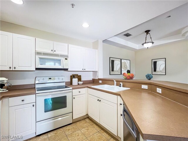 kitchen featuring white appliances, visible vents, a peninsula, a tray ceiling, and a sink