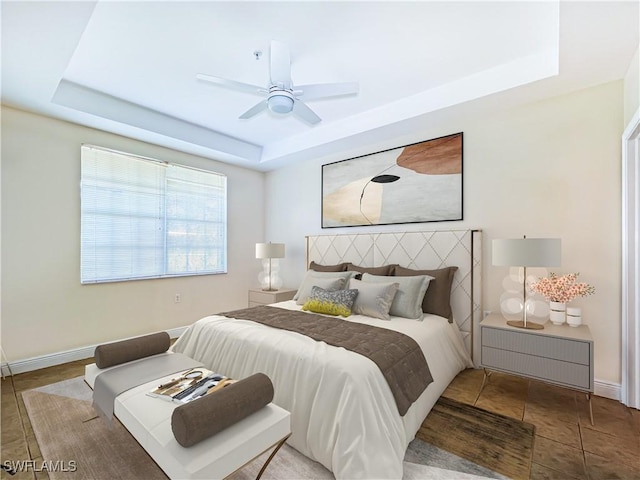 bedroom featuring ceiling fan, baseboards, and a tray ceiling