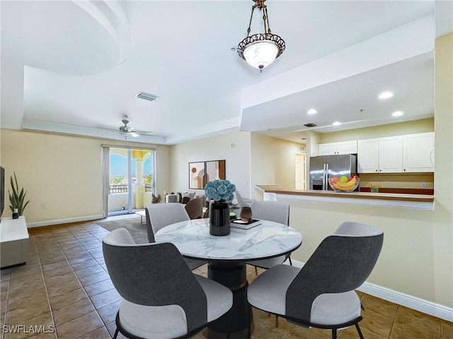 dining space featuring tile patterned floors, a raised ceiling, and ceiling fan