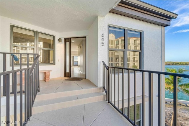 doorway to property with a balcony and a water view