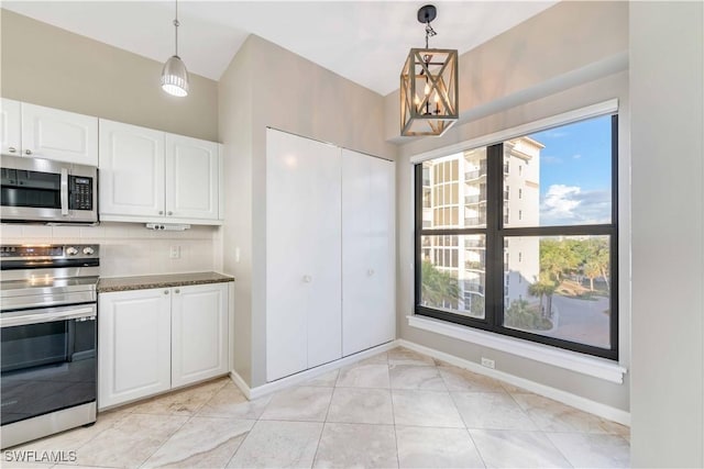 kitchen featuring decorative backsplash, appliances with stainless steel finishes, dark stone counters, decorative light fixtures, and white cabinetry