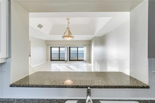 kitchen with white cabinetry, sink, a raised ceiling, dark stone counters, and pendant lighting