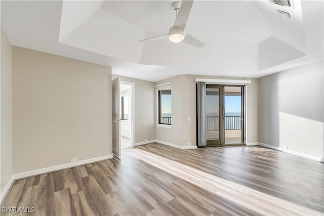 spare room with a raised ceiling, ceiling fan, and hardwood / wood-style floors