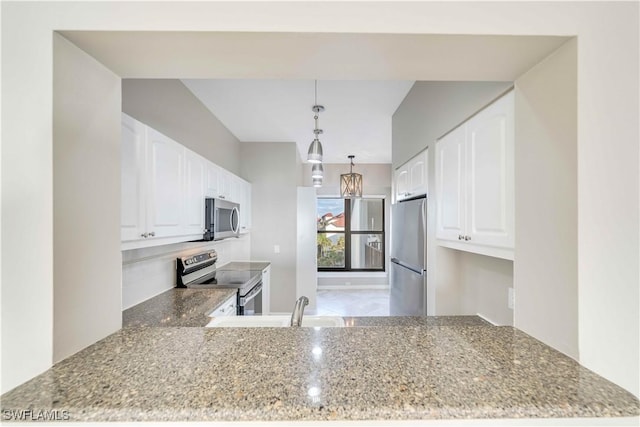 kitchen featuring kitchen peninsula, light stone counters, stainless steel appliances, decorative light fixtures, and white cabinetry