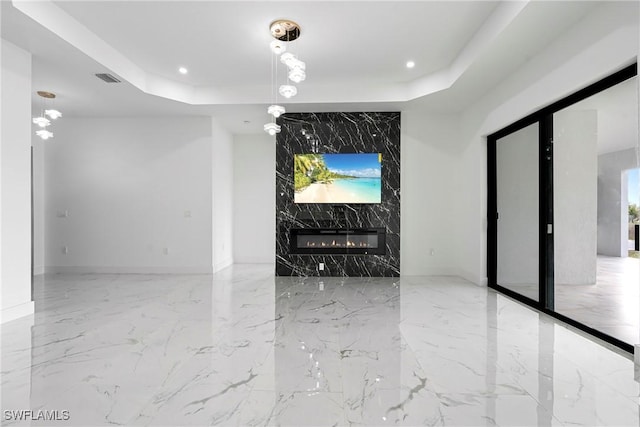 unfurnished living room featuring a raised ceiling and a fireplace