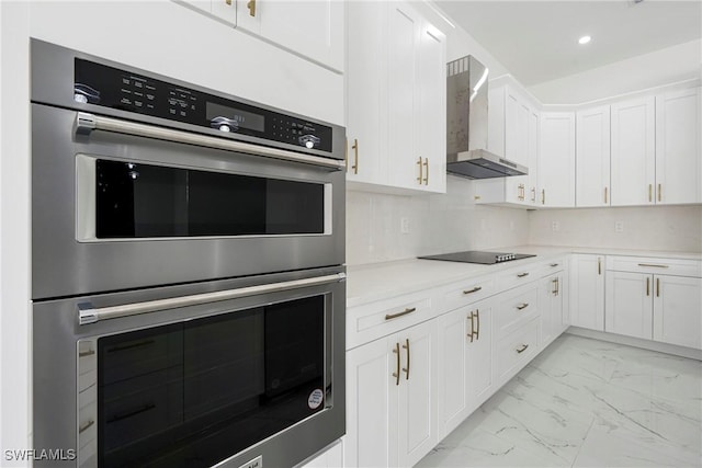 kitchen with white cabinets, black electric stovetop, wall chimney range hood, and double oven