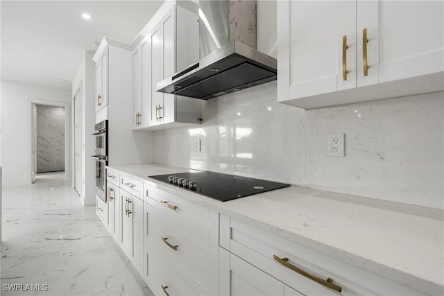 kitchen featuring white cabinetry, light stone countertops, wall chimney range hood, double oven, and black electric cooktop