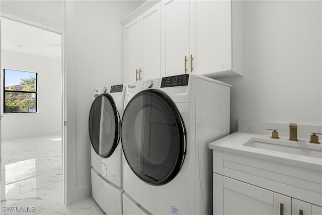 laundry area featuring washing machine and dryer, sink, and cabinets