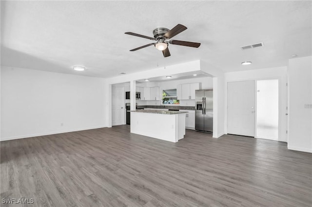 unfurnished living room featuring dark wood-style floors, baseboards, visible vents, and a ceiling fan