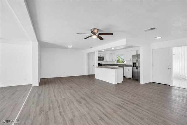 unfurnished living room with dark wood finished floors, visible vents, ceiling fan, and baseboards