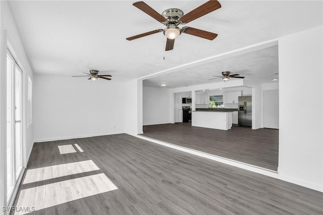 unfurnished living room featuring dark wood-type flooring and baseboards