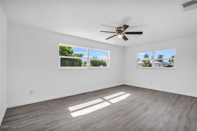 spare room featuring a ceiling fan, wood finished floors, visible vents, and baseboards