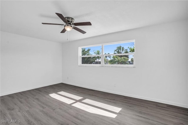 spare room featuring dark wood-style floors, baseboards, and a ceiling fan