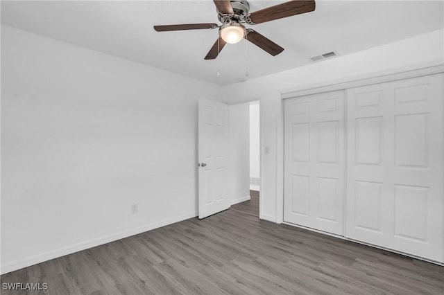 unfurnished bedroom featuring dark wood-style floors, a closet, visible vents, ceiling fan, and baseboards