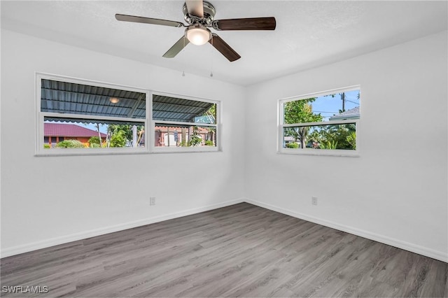 empty room with a ceiling fan, baseboards, and wood finished floors