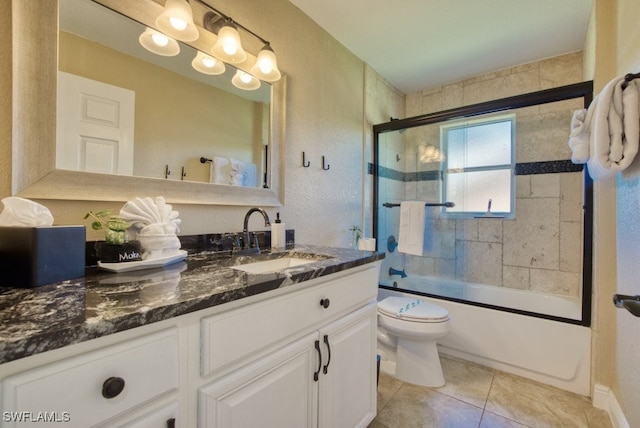 full bathroom with combined bath / shower with glass door, vanity, toilet, and tile patterned flooring