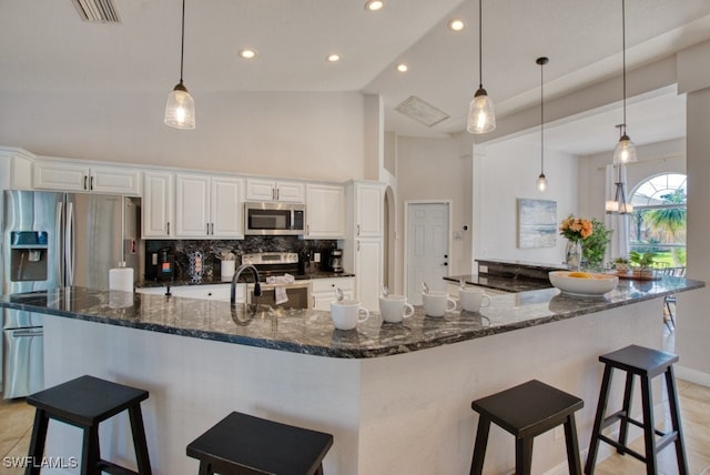 kitchen with dark stone counters, white cabinets, high vaulted ceiling, and appliances with stainless steel finishes