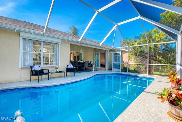 view of pool with glass enclosure, ceiling fan, and a patio area