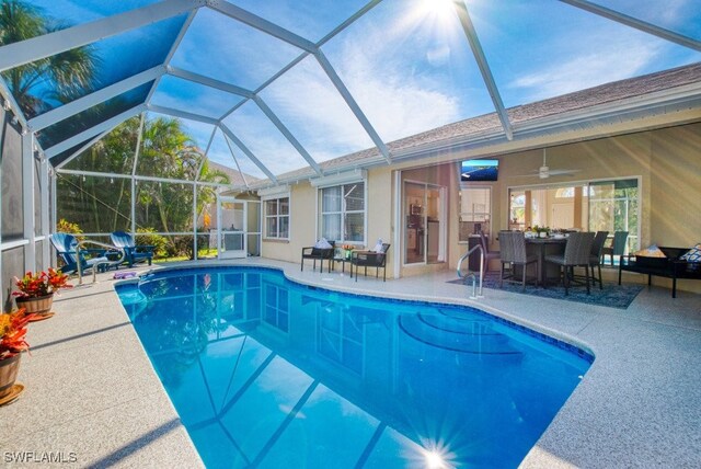 view of swimming pool featuring glass enclosure, ceiling fan, and a patio