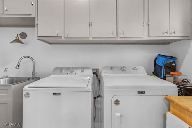 laundry area featuring cabinets, washing machine and clothes dryer, and sink