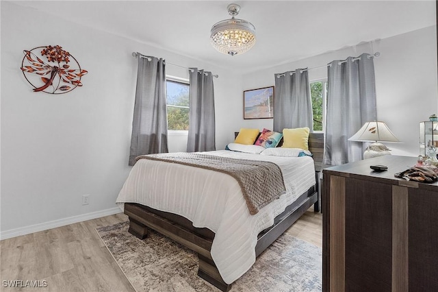 bedroom featuring light hardwood / wood-style floors, a notable chandelier, and multiple windows