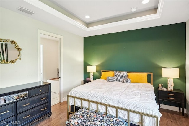 bedroom with hardwood / wood-style floors and a tray ceiling