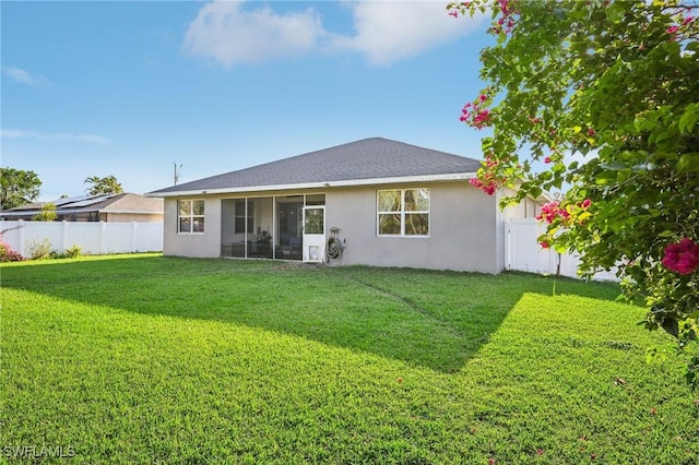 rear view of property with a lawn and a sunroom