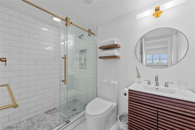 bathroom featuring toilet, a shower with shower door, and vanity