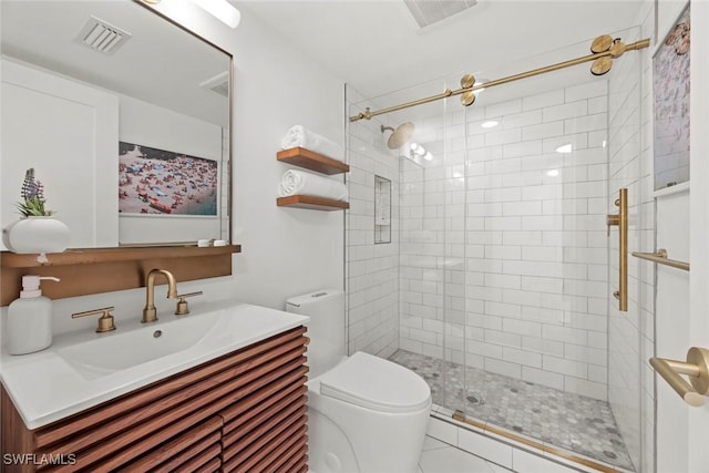 bathroom with toilet, tile patterned flooring, a tile shower, and vanity