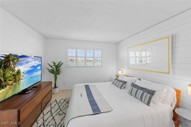 bedroom featuring wooden walls and light hardwood / wood-style flooring