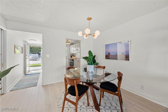 dining area featuring a textured ceiling, light hardwood / wood-style flooring, and a chandelier