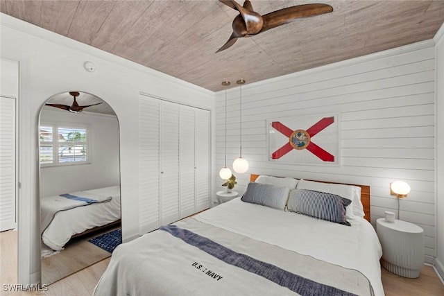 bedroom with ceiling fan, wood ceiling, light hardwood / wood-style flooring, and wooden walls