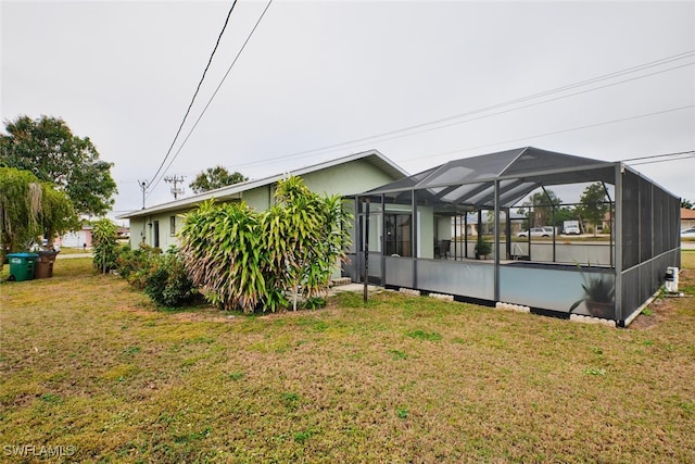 back of property featuring a lanai and a lawn