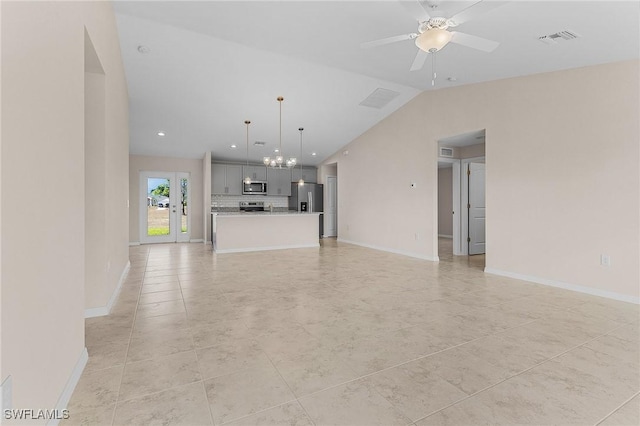 unfurnished living room featuring ceiling fan with notable chandelier and vaulted ceiling