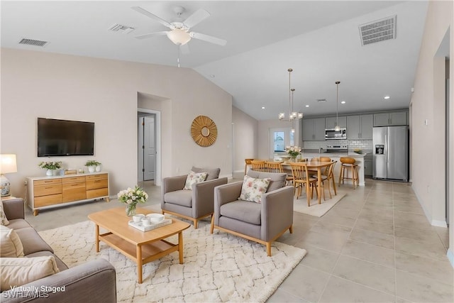 living room with lofted ceiling, ceiling fan with notable chandelier, and light tile patterned flooring