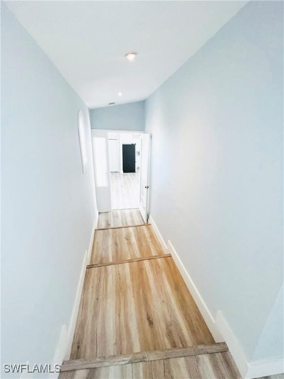 hall with light hardwood / wood-style flooring and lofted ceiling