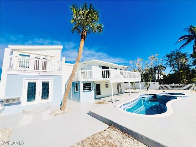 back of house with a patio area, a balcony, french doors, and a pool with hot tub