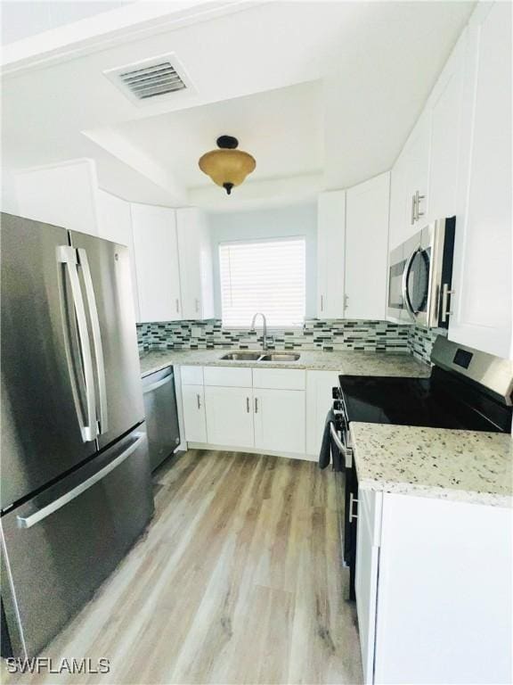 kitchen featuring light stone counters, sink, white cabinets, and stainless steel appliances