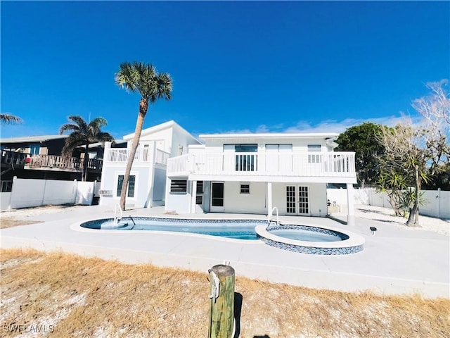 back of property with a pool with hot tub, a balcony, a patio, and french doors