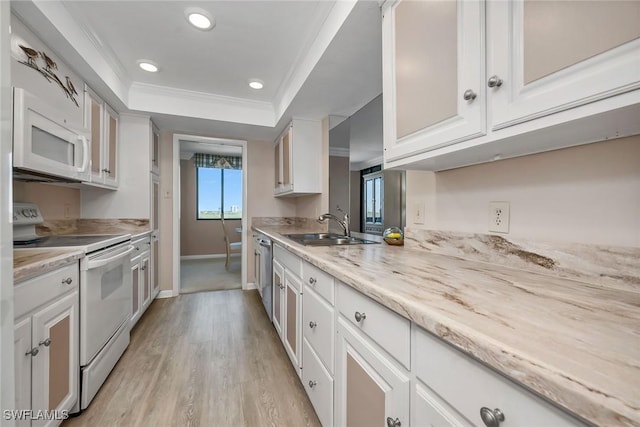 kitchen with white cabinetry, sink, light hardwood / wood-style floors, white appliances, and a tray ceiling