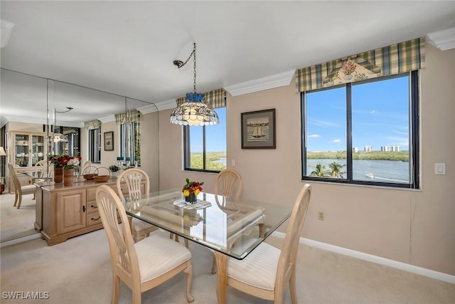 dining space featuring light carpet, a water view, and crown molding