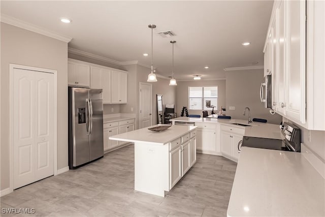 kitchen with stainless steel appliances, sink, pendant lighting, white cabinets, and an island with sink