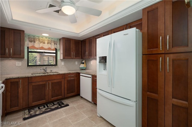 kitchen featuring white appliances, light stone counters, a raised ceiling, and sink